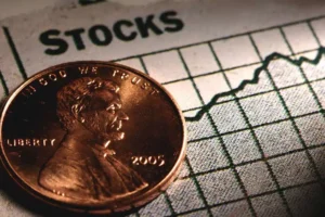 A single penny placed on a stock chart, illustrating the Difference Between Stocks and Cryptocurrencies.